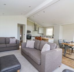 A living room with two sofas, an ottoman, and an open kitchen and dining area at Seren Lodge in Builth Wells