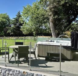 An outdoor patio with a round table and four chairs next to a hot tub with water jets at Towy Cottage Cardigan Near Cenarth