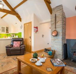 A living room with a fireplace a coffee table and a leather armchair at Gwaun Cottage Cardigan Near Cenarth