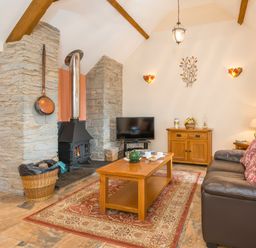 A living room with a wood stove television wooden furniture and a leather sofa at Gwaun Cottage Cardigan Near Cenarth