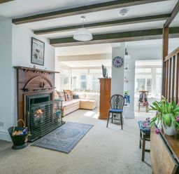 A living room with a wooden fireplace a carpet and a sofa near windows at The Harbour in Rhosneigr