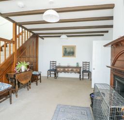 A room with wooden stairs two chairs a table and a fireplace at The Harbour in Rhosneigr