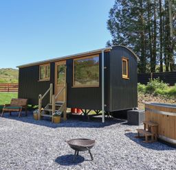 An outdoor area with a black corrugated small cabin wooden bench fire pit and wooden hot tub at Celyn in Bontddu near Dolgellau