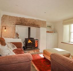 A living room with a fireplace and sofa at Poldue House in Watergate near Camelford