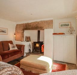 A living room with a fireplace and sofa at Poldue House Watergate near Camelford