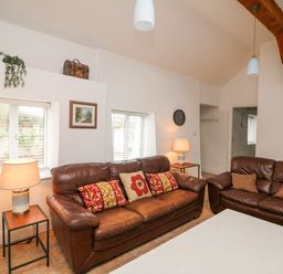 A living room with two brown leather sofas and table lamps on side tables at Bayside Cottage in Rosslare Strand County Wexford