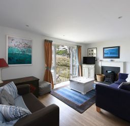 A living room with sofas a rug a coffee table a fireplace and a TV at Northern Lights in Polzeath