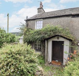 A cottage entrance surrounded by plants and a path at Old Cottage in Oxen Park near Ulverston