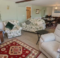 A living room with floral armchairs a gray recliner a red patterned rug and a dining table at Chapel Hill House Chapel Hill near Pembroke