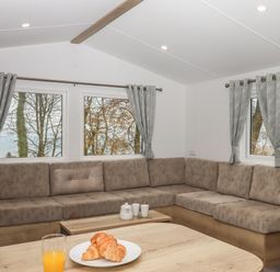 A living room with an L shaped sofa and gray curtains on windows at 5 Manor Park in Bucks Cross Bideford