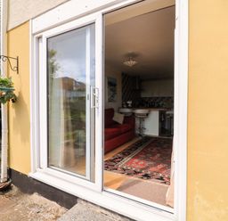 A living room with a sliding door and a couch at Garden View in Hillhead near Brixham