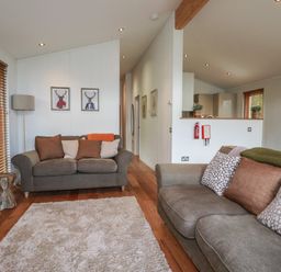 A living room with two sofas a floor lamp and framed pictures on the wall at 3 Hedgerows in Lanreath