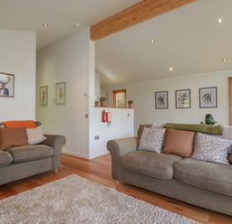 A living room with two grey sofas cushions framed prints and wooden floors at 3 Hedgerows in Lanreath
