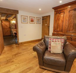 A room with a brown leather armchair with cushions wooden furniture wooden floor and two wooden doors at Ysgubor in Dinas Mawddwy near Dolgellau