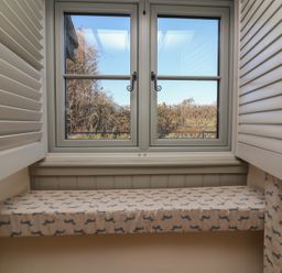 A window with open shutters and a cushioned window seat covered in fabric with a dachshund pattern at Curlew Cottage North Curry near Taunton