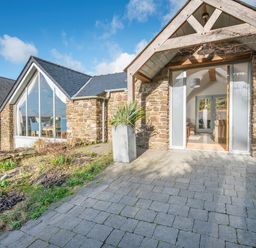 Stone exterior cottage with large windows and potted plant on paved patio at Leeward Cottage in Cosheston near Pembroke Dock