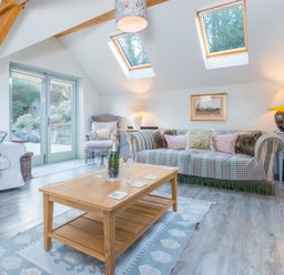 A living room with sofas a wooden coffee table and skylights at Leeward Cottage in Cosheston near Pembroke Dock