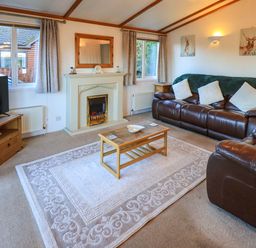 A living room with leather sofas a fireplace a coffee table and a television at Lavender Lodge South Lakeland Leisure Village
