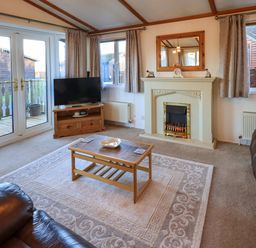 A living room with a coffee table TV and fireplace at Lavender Lodge in South Lakeland Leisure Village