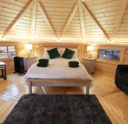 A bedroom with a bed a gray rug a black sofa and wooden walls at The Hideaway in Dungiven Londonderry