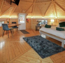 A wooden interior room with a bed table and chairs a rug and a door at The Hideaway in Dungiven Londonderry