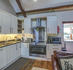 A kitchen with white cabinets a black countertop a stainless steel oven and stove a microwave and a coffee maker at Upper Calffield Barn Camrose near Haverfordwest