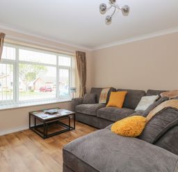 A living room with grey sofas and a coffee table in front of a large window at White Lion Retreat in Cromer