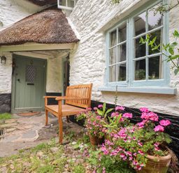 A garden with a bench and flower pots at 3 Cumberland Cottages Ringmore