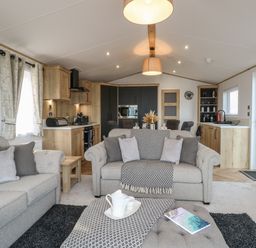 A living room with sofas and a coffee table next to a kitchen in Dorchester in Broomholm near Mundesley