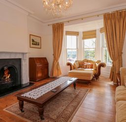 A living room with a fireplace wooden coffee table sofas and a bay window at Fir Grove in Menai Bridge