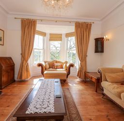 A living room with a sofa armchair wooden coffee table and curtains at Fir Grove in Menai Bridge