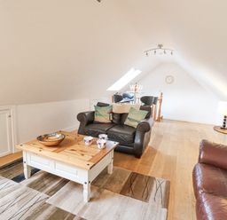 A loft living room with leather sofas wooden coffee table and bar stools at Trevone in Goodwick