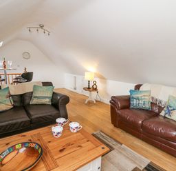 A living room with two leather sofas wooden coffee table with cups and bowl and a lamp on a side table at Trevone in Goodwick