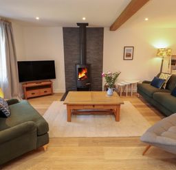 A living room with a TV and a fireplace at Bramble Cottage Thornthwaite near Braithwaite