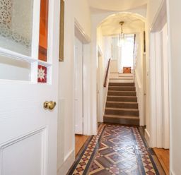 A hallway with patterned tile floor leading to carpeted stairs at Middletown in Keswick