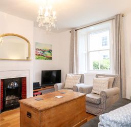 A living room with armchairs a wooden chest a small fireplace a television and a large window at Middletown in Keswick
