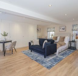 A bedroom with a navy blue sofa and bed on a blue rug near a dining table with chairs at Providence Court Near Easingwold