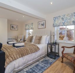 A bedroom with a bed sofa armchair wooden chair and side tables at Providence Court Near Easingwold