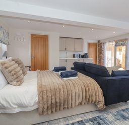 A bedroom with a bed a sofa a kitchenette and large windows at Providence Court Near Easingwold