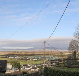 A rural landscape with houses fields and gravestones on a hill at Gwelfor in Harlech