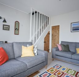 A living room with two gray sofas with colored cushions and a patterned rug at Gwelfor in Harlech