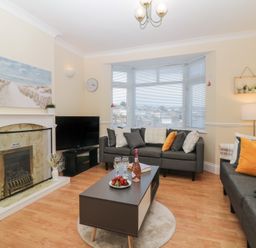A living room with two gray sofas a coffee table a fireplace and a television at Hilltop Cottage in Paignton