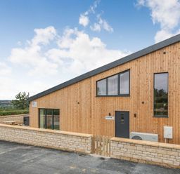 Exterior view of a wooden building with stone wall and gate at Bears Court Barn 1 in Little Rissington near Bourton-On-The-Water