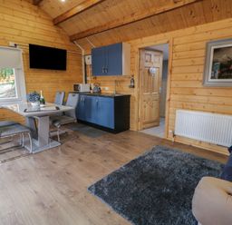 A small kitchen and dining area with a table, chairs, and blue cabinets in a wooden room at Drumrane Lodge in Dungiven Londonderry