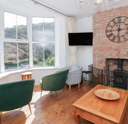 A living room with a fireplace and chairs at Brynmorfa in Llandysul