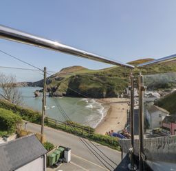 A view of a beach and hills from a balcony at Brynmorfa in Llandysul