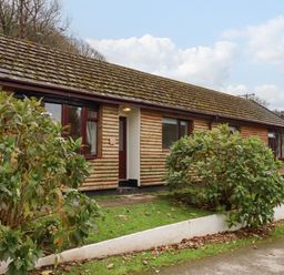 A single story wooden house with bushes in front at Castle View Lodge in Ilfracombe