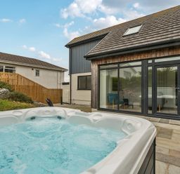 An outdoor area with a hot tub and stone patio at Seaddler in Trearddur Bay