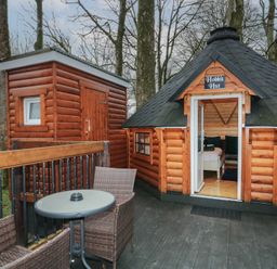 An outdoor deck with a round table and two wicker chairs next to a wooden hut labeled Hobbit Hut in Dungiven Londonderry