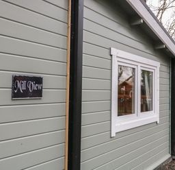 The exterior side wall of a building with a white-framed window and a sign that reads Mill View near two trees at Mill View in Dungiven Londonderry